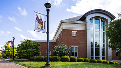 green shrubs surrounding the student center building on a sunny day with a bright
                        blue sky