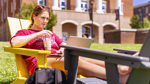 A student using a laptop outside on a sunny day