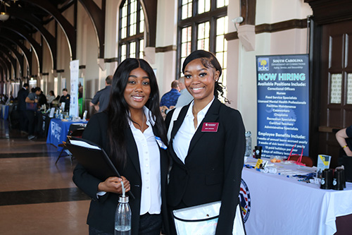 Two students in professional attire posing at a Career Fair event