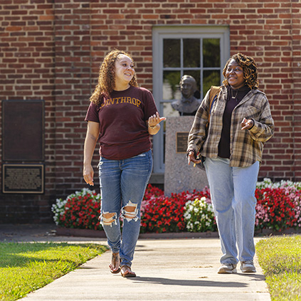 Two students walking outside the Little Chapel on a sunny day