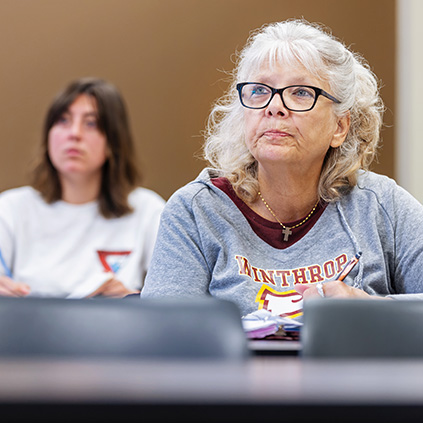 A senior citizen women listening to a lecture in a classroom