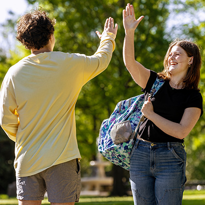 Two students high-fiving with smiles on their faces