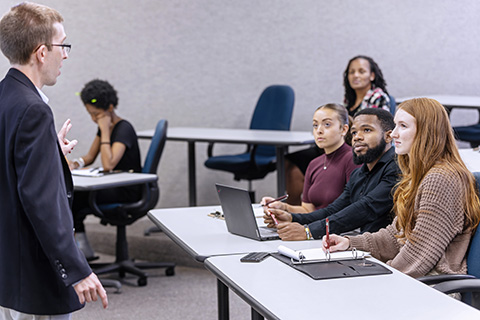 Graduate students sitting in a lecture hall listening to the professor