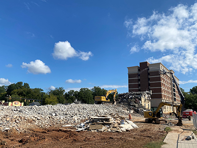 Blue sky with high rise building the background and debris and rubble in the foreground