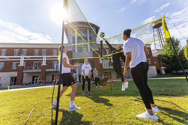 students playing volleyball on the campus green behind the student center