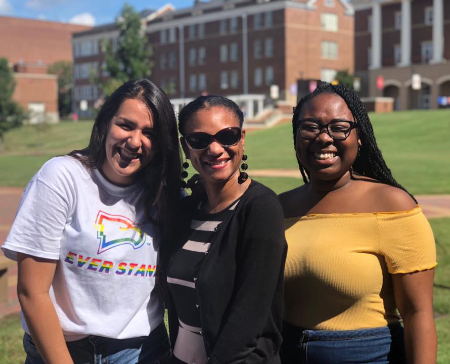 students standing with a staff member on the campus green. One of them is wearing
                              a rainbow Winthrop shirt