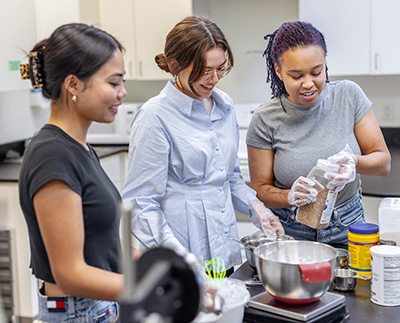 three human nutrition students working in a food lab