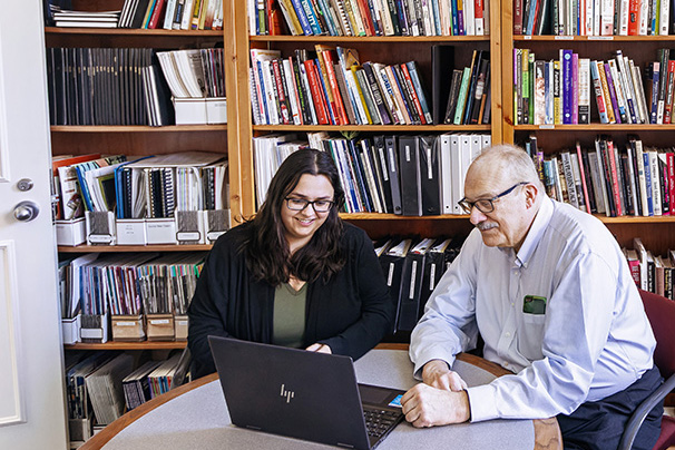 a graduate student and staff member looking at a laptop together in an office