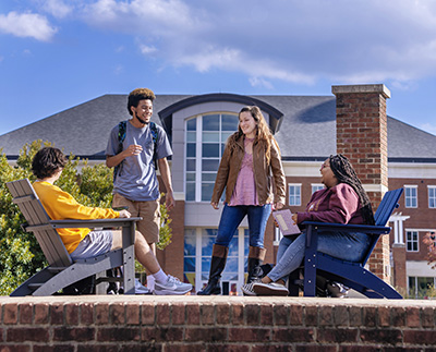 a group of students sitting in colorful adirondack chairs and laughing together