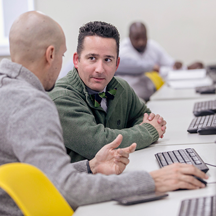 two adult professionals having a discussion in a computer lab