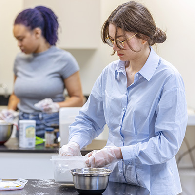 Student measuring ingredients at a food prep station