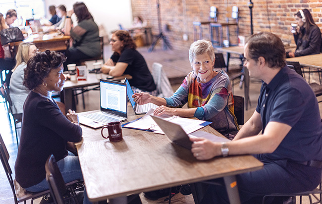 Three adults working on laptops at a table together