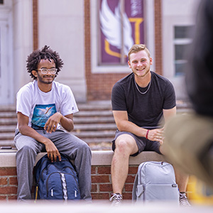 two students laughing while one carries the other on her back