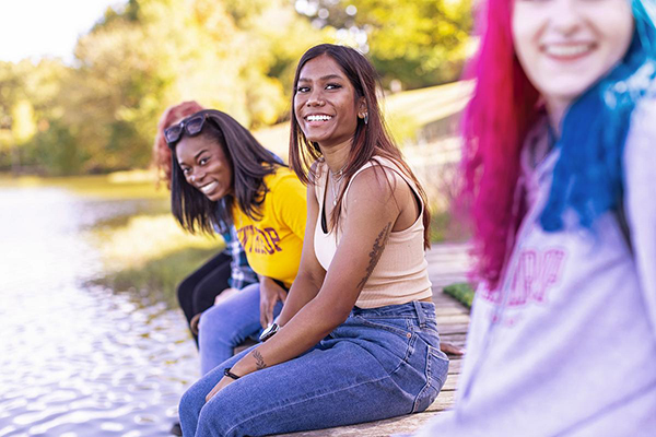 students sitting on the dock by the lake on a sunny day